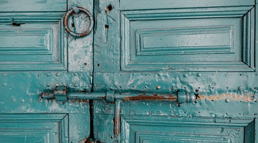 An old green door locked with a bolt.
