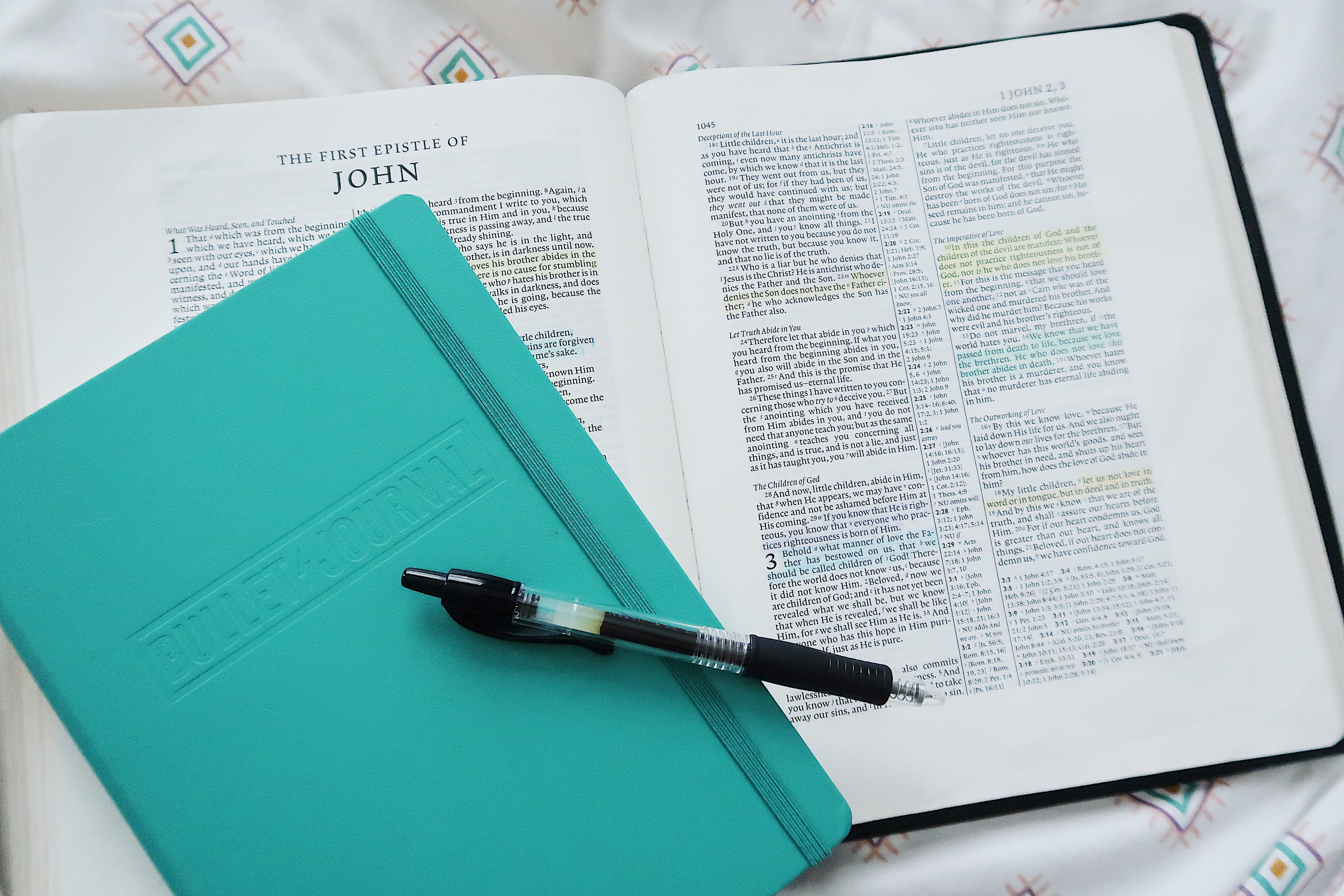 A bible with a coloured notepad and pen on top of it